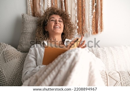 Woman reading funny book on bed