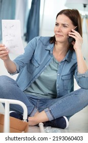 Woman Reading Furniture Assembly Instructions And Making Telephone Call