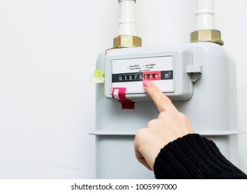 Woman reading the gas meter in the private house, counter for distribution domestic gas. Cropped image, selective focus. - Shutterstock ID 1005997000