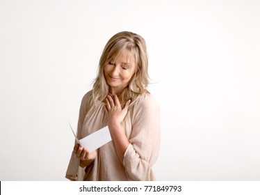 Woman Reading A Heartfelt Message, Note, Book Or Card.   She Is Smiling And Has Her Hand To Heart. White Background