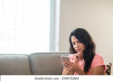 Woman Reading Her Messages On Her Phone Looking Concerned. 