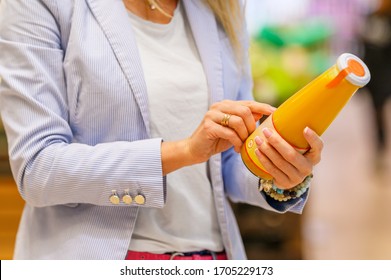 Woman reading ingredients and nutrition information on juice bottle's etiquette 