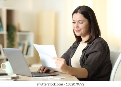 Woman reading a letter using laptop sitting in a table at home