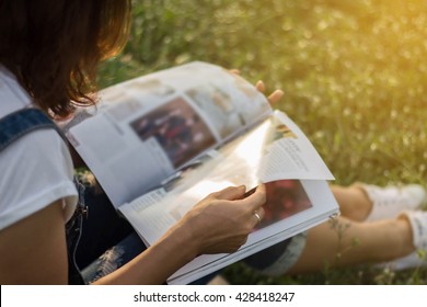 Woman Reading A Magazine In Garden.