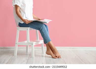 Woman Reading Magazine On White Step Stool Near Pink Wall