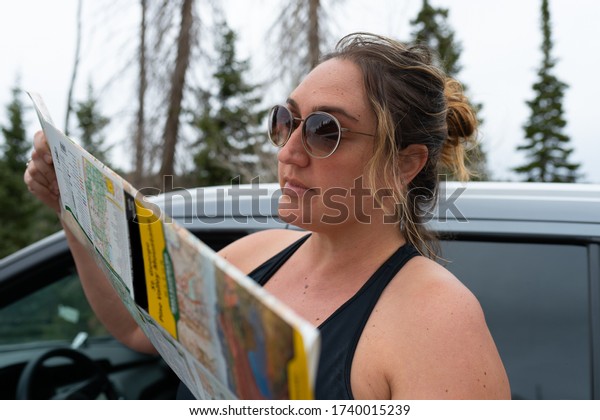 a\
woman reading a map on the side of the road\
outside