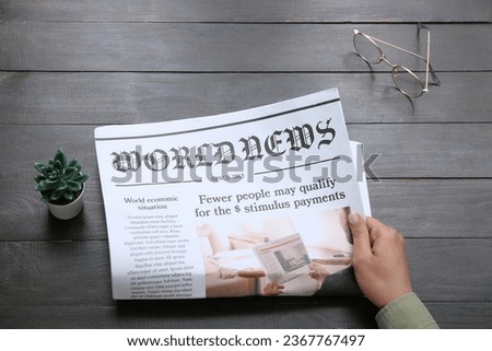 Woman reading newspaper on black wooden background