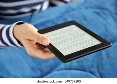Woman reading a novel on a tablet in bed.