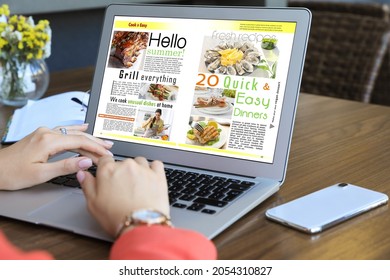 Woman Reading Online Magazine On Laptop At Wooden Table, Closeup