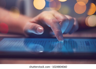 Woman reading online news on digital tablet, close up of hands using device