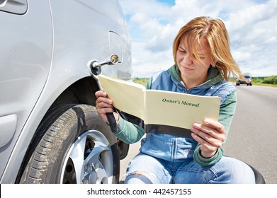 Woman Reading Owner's Manual Of Her Car