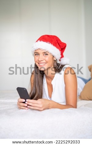 Woman reading phone content at christmas lying on bed in room