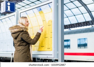 Woman reading time table in train station pinned on a board
