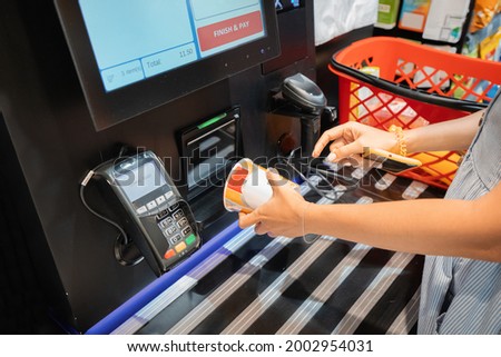 A woman reads the bar code of instant noodles soup at the self-service checkout machine in supermarket