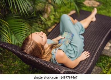 Woman reads e-book on deck chair in the garden - Shutterstock ID 1499799467