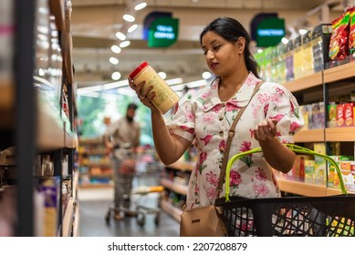 Woman Reads Product Label At Supermarket.