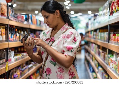 Woman Reads Product Label At Supermarket.