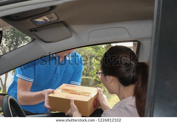 woman\
receive package from delivery man. male postal courier person\
deliver cardboard box to female adult on\
car