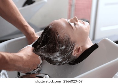 Woman receives hair washing procedure in salon. Concept of spa services. Fashionable lifestyle. - Shutterstock ID 2366020459