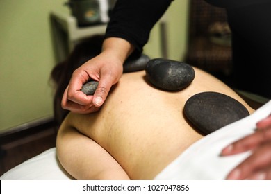 A Woman Receives A Hot Stone Massage, A Procedure Where The Therapist Uses Smooth, Heated Stones As An Extension Of Their Own Hands.