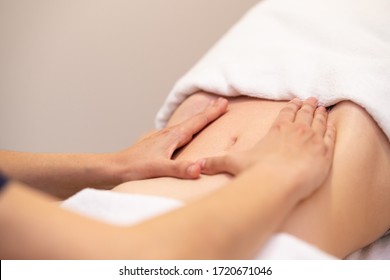 Woman receiving a belly massage at spa salon. Female patient is receiving treatment by professional osteopathy therapist.