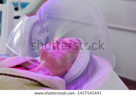 Woman receiving color light therapy for face. Facial therapy. Anti-aging procedures.