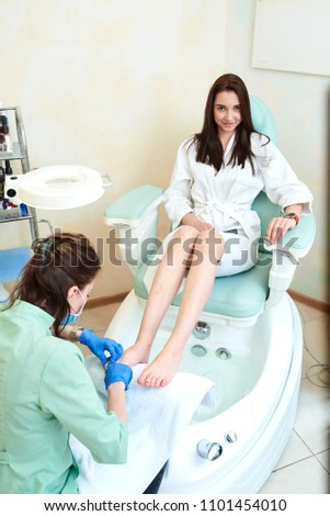 Woman receiving cuticle in manicure pedicure salon. Patient on medical pedicure procedure, visiting podiatrist. Foot treatment in SPA salon. Podiatry clinic.