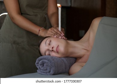 Woman receiving ear candle treatment at spa. Ear coning or thermal-auricular therapy. - Powered by Shutterstock