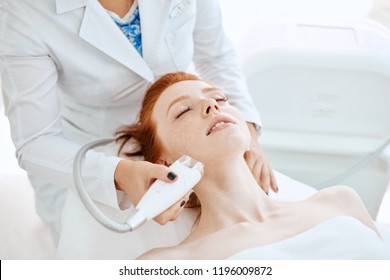 Woman Receiving Electric Facial Ultrusound Peeling At Modern Beauty Salon. Female Patient Getting Radio Frequency Lifting On Her Face.