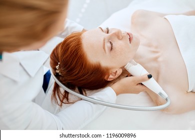 Woman Receiving Electric Facial Ultrusound Peeling At Modern Beauty Salon. Female Patient Getting Radio Frequency Lifting On Her Face.