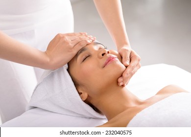 Woman receiving facial massage in spa salon