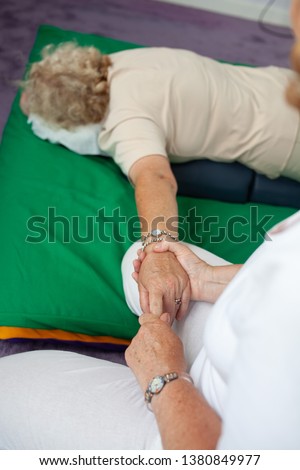 A woman receiving a hand massage lying on a mat