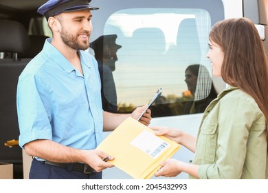 Woman Receiving Letter From Postman Outdoors