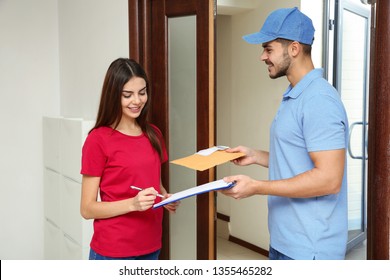 Woman receiving padded envelope from delivery service courier indoors