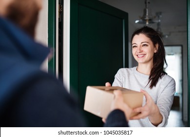 Woman receiving parcel from delivery man at the door. - Shutterstock ID 1045035817