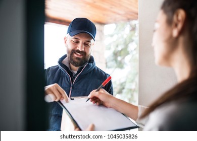 Woman Receiving Parcel From Delivery Man At The Door.