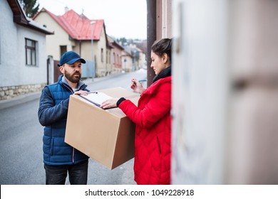 Woman Receiving Parcel From Delivery Man At The Door.