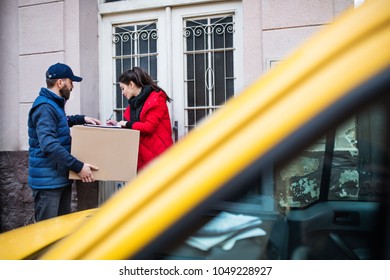 Woman Receiving Parcel From Delivery Man At The Door.