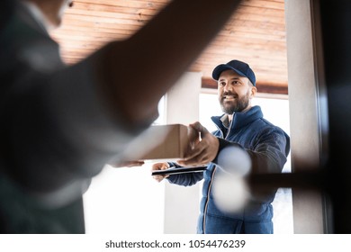 Woman Receiving Parcel From Delivery Man At The Door.