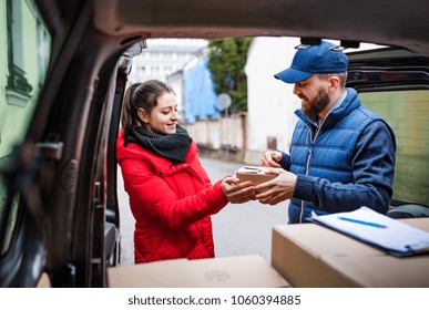 Woman Receiving Parcel From Delivery Man.