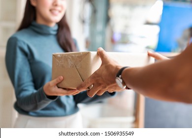 Woman Receiving Parcel From Hands Delivery Man At The Door.