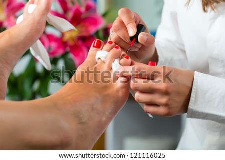 Woman receiving pedicure in a Day Spa, feet nails get polish
