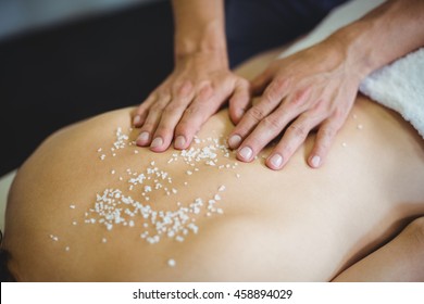 Woman receiving salt scrub therapy from physiotherapist in clinic - Powered by Shutterstock