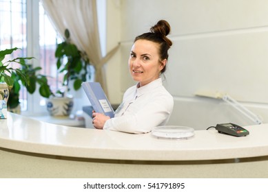 Woman receptionist in medical coat stands at reception desk