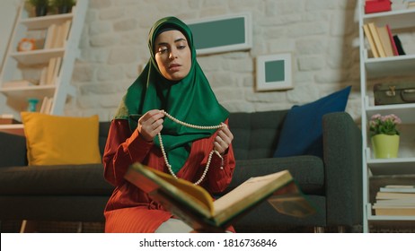 A Woman Reciting The Quran And Drawing A Rosary On The Sofa During A Ramadan Holiday At Home.