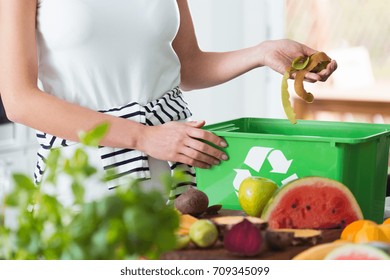 Woman recycling organic kitchen waste by composting in green container during preparation of meal - Powered by Shutterstock