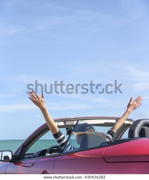  Woman in red cabriolet \
car at background of sea water. Travel, freedom and holidays\
concept.