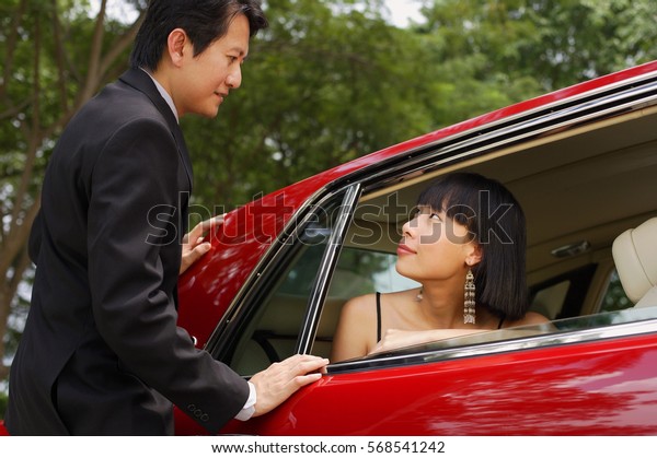 Woman in red\
car, man standing next to door of\
car