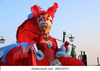 A Woman In A Red Carnival Costume Of Marie Antoinette And A Mask Holds A Red Umbrella On The Embankment In Venice Italy, February 20, 2017