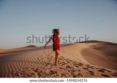Woman in red dress in the desert dunes